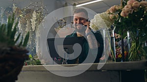 Male entrepreneur florist talks by phone and uses tablet