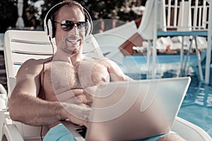 Male entrepreneur grinning broadly while working at swimming pool