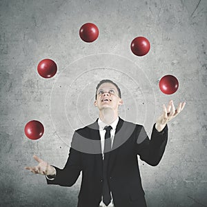 Male entrepreneur juggling many red balls