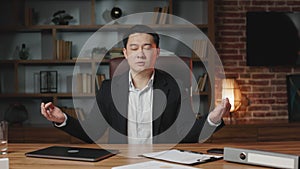Male entrepreneur meditating with closed eyes in office