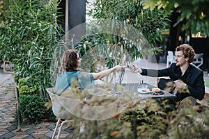 Male entrepreneur passing a notebook to his female partner while having meeting in urban coffee bar.