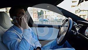 Male entrepreneur speaking by smartphone during riding on electrical auto with autopilot at urban road. Confident photo