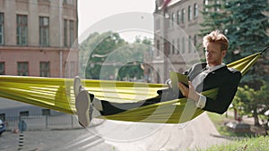 Male entrepreneur in suit working on tablet in hammock