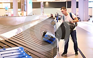 A male European traveler passenger picks up his luggage from the  baggage claim tape upon arrival departure at the Havalimani