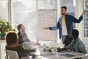 Male executive explaining business plans to his coworkers on flip chart