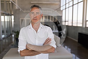 Male executive standing with arms crossed in office