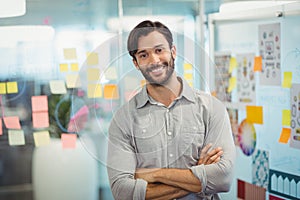 Male executive standing with arms crossed in office