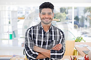 Male executive standing with arms crossed in the office