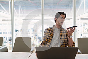 Male executive talking on mobile phone using laptop in the conference room