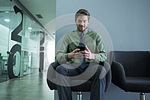 Male executive using mobile phone in waiting area