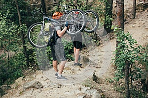 male extreme cyclists in helmets carrying mountain bikes