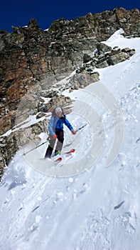 Male extreme skier skiing down a very steep couloir in deep winter in the Swiss Alps near Klosters