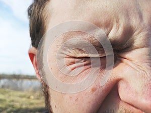 The male eye frowns from the sun. Men`s facial wrinkles