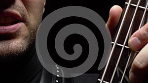 Male face and fretboard of electric guitar  on black background.