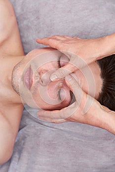Male face, hands of masseuse.