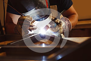 Male in face mask welds with argon-arc welding photo