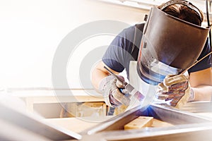 Male in face mask welds with argon-arc welding