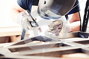 Male in face mask welds with argon-arc welding