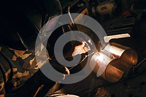 Male in face mask welds with argon welding. Industrial welder worker welding using argon machine, close up. Man working