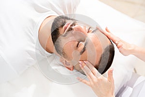 Male face massage for reducing puffiness by professional massage therapist photo