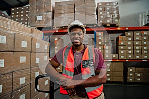 Male factory worker smiling besides packages in warehouse