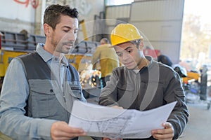 Male factory worker and supervisor analyzing plans