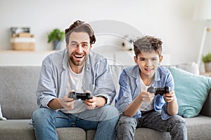 Male family leisure. Happy father and his son playing online video games and competing, using joysticks