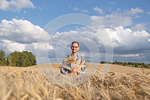 Male farmer or baker with baguettes in rye, wheat field