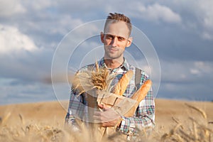 Male farmer or baker with baguettes in rye, wheat field