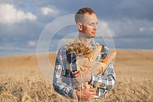 Male farmer or baker with baguettes in rye, wheat field