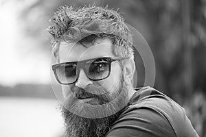 Male fashion concept. Guy looks confident with stylish sunglasses. Man with beard and mustache wears sunglasses, river