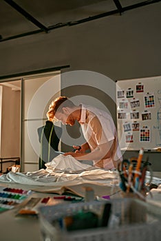 Male fashion designer cutting cloth with scissors