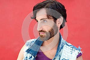 Male fashion model with beard posing on red background