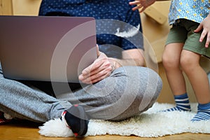 A male father working from home using a laptop and nearby his little son playing with children`s toys.
