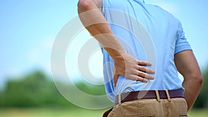 Male feeling sharp lower back pain outdoor, health and problems, medicine photo