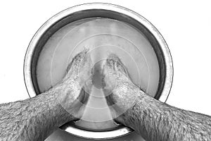 Male feet in a basin with mustard soars his legs, on a white natural background