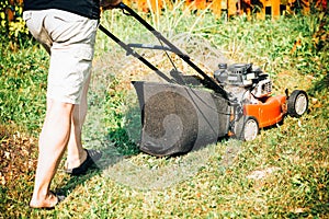 Male feet with electric lawnmower, lawn mowing