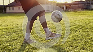 Male feet of professional footballer kicking ball at green field. Legs of young man juggling soccer ball on stadium at