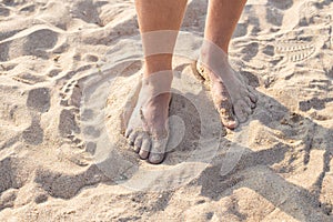 Male feet in the sand. Walk along the sandy sea beach on a summer day. Travel and tourism