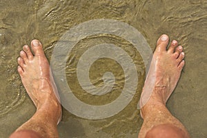 Male feet on sandy beach