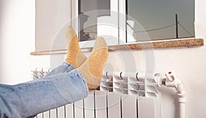 Male feet with socks on the radiator. Heating season