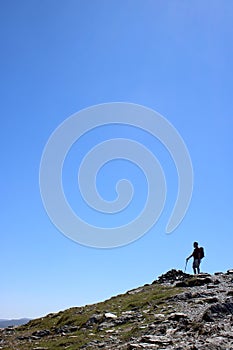 Male fellwalker on skyline on mountain footpath photo