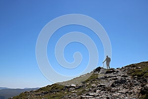 Male fellwalker on skyline on mountain footpath photo