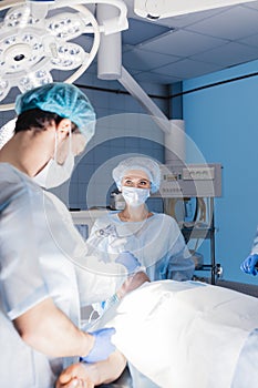 Male and female anesthetists preparing patient before operation in hospital