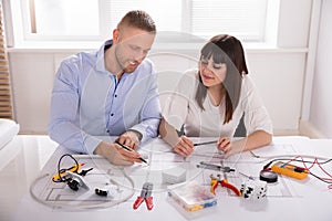 Male And Female Architect Working On Blueprint