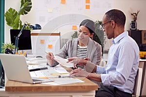 Male And Female Architects Or Interior Designers Working In Office On Plans For New Building