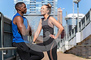 Male and female athlete fitness and exercise friends smiling, cheerful, flirting, happy, and laughing together with city backgroun