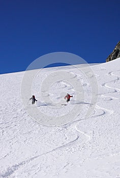 Male and female backcountry skiers draw first tracks in the fresh powder snow in the Alps
