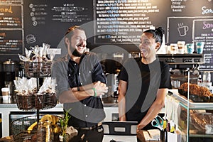 Male And Female Baristas Behind Counter In Coffee Shop