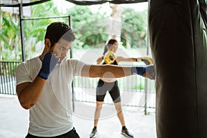 the male and female boxer hitting the sand bag